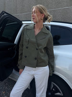 Modelfoto af pige der bærer Carlie jakke i kaki, samt hvid bukser. Alt fra BySofieSønderby