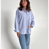 Modelfoto af pige der bærer en lyseblå stribet Caro skjorte, samt blå Nanna jeans. Alt fra BySofieSønderby