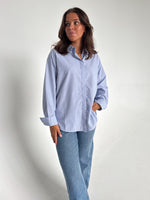 Modelfoto af pige der bærer en lyseblå stribet Caro skjorte, samt blå Nanna jeans. Alt fra BySofieSønderby
