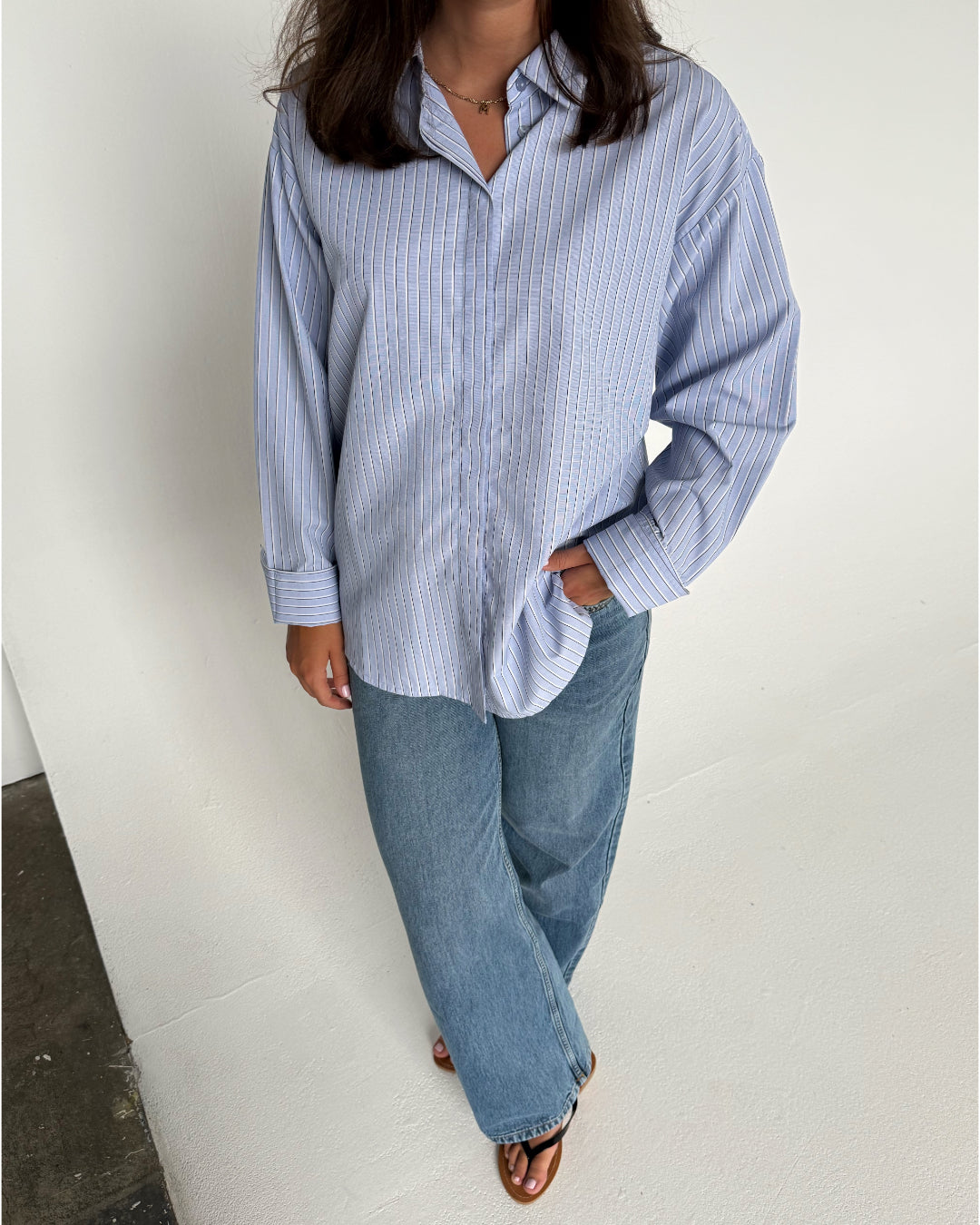 Modelfoto af pige der bærer en lyseblå stribet Caro skjorte, samt blå Nanna jeans. Alt fra BySofieSønderby