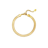 Et guldarmbånd ligger i en cirkulær form med en lille justerbar kæde og vedhæng. Armbåndet hviler på en hvid baggrund og vedhænget har en indgravering.