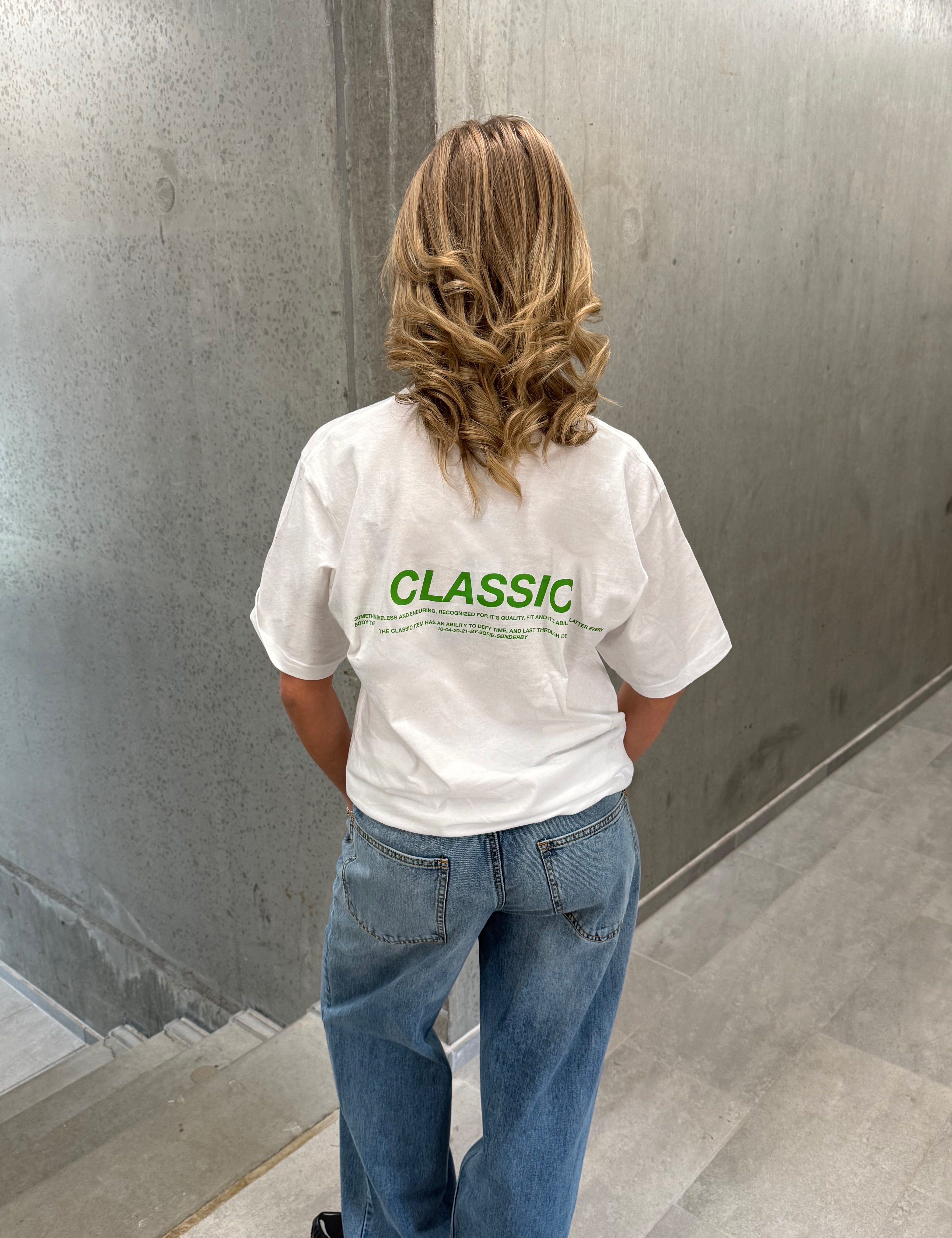 Stemningsbillede af pige der bærer en hvid t-shirt med grønt classic tryk og blå NANNA jeans.  Fra BySofieSønderby