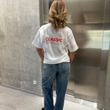 Stemningsbillede af pige der bærer en hvid t-shirt med rødt classic tryk og blå NANNA jeans.  Fra BySofieSønderby