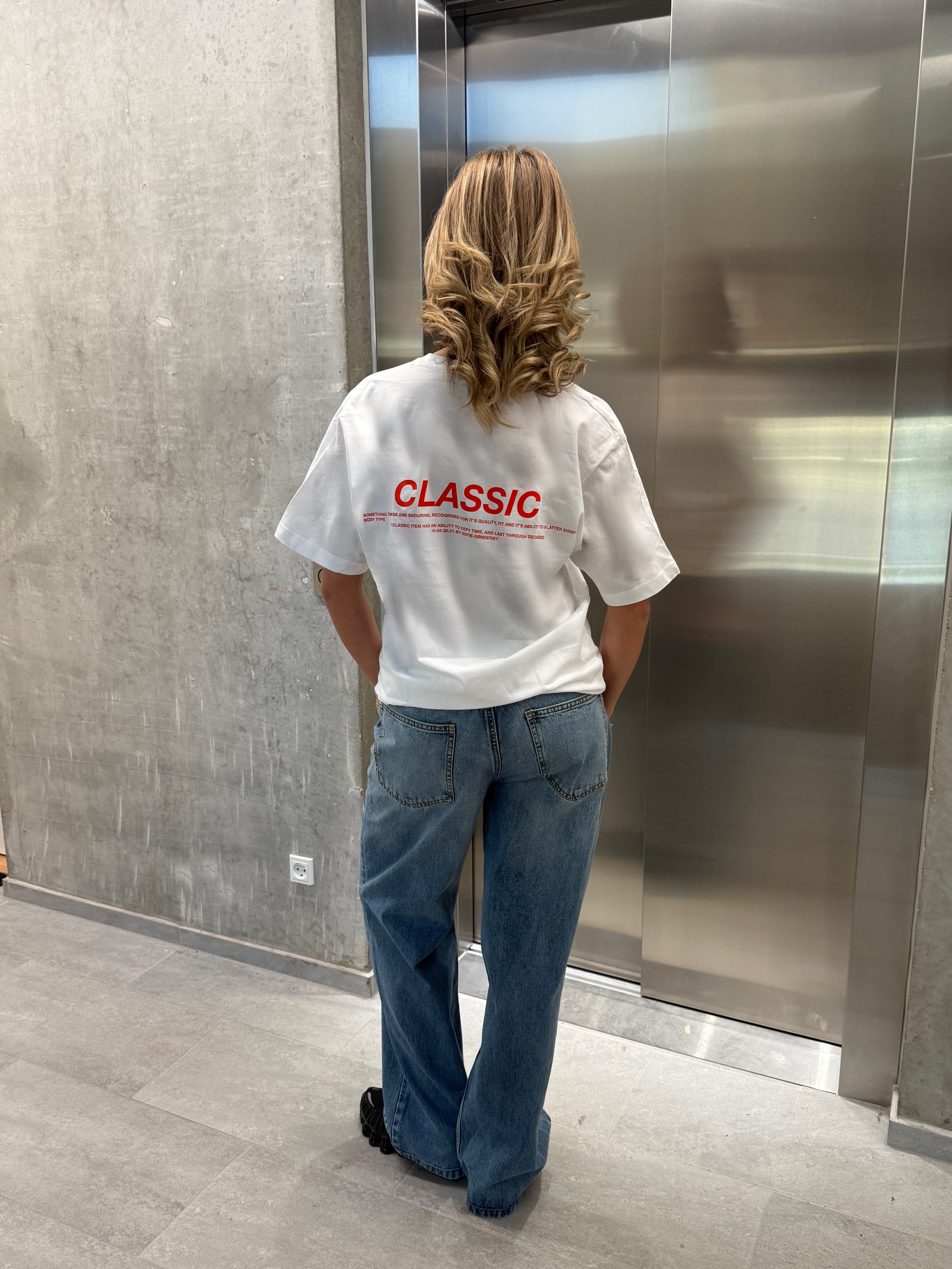 Stemningsbillede af pige der bærer en hvid t-shirt med rødt classic tryk og blå NANNA jeans.  Fra BySofieSønderby