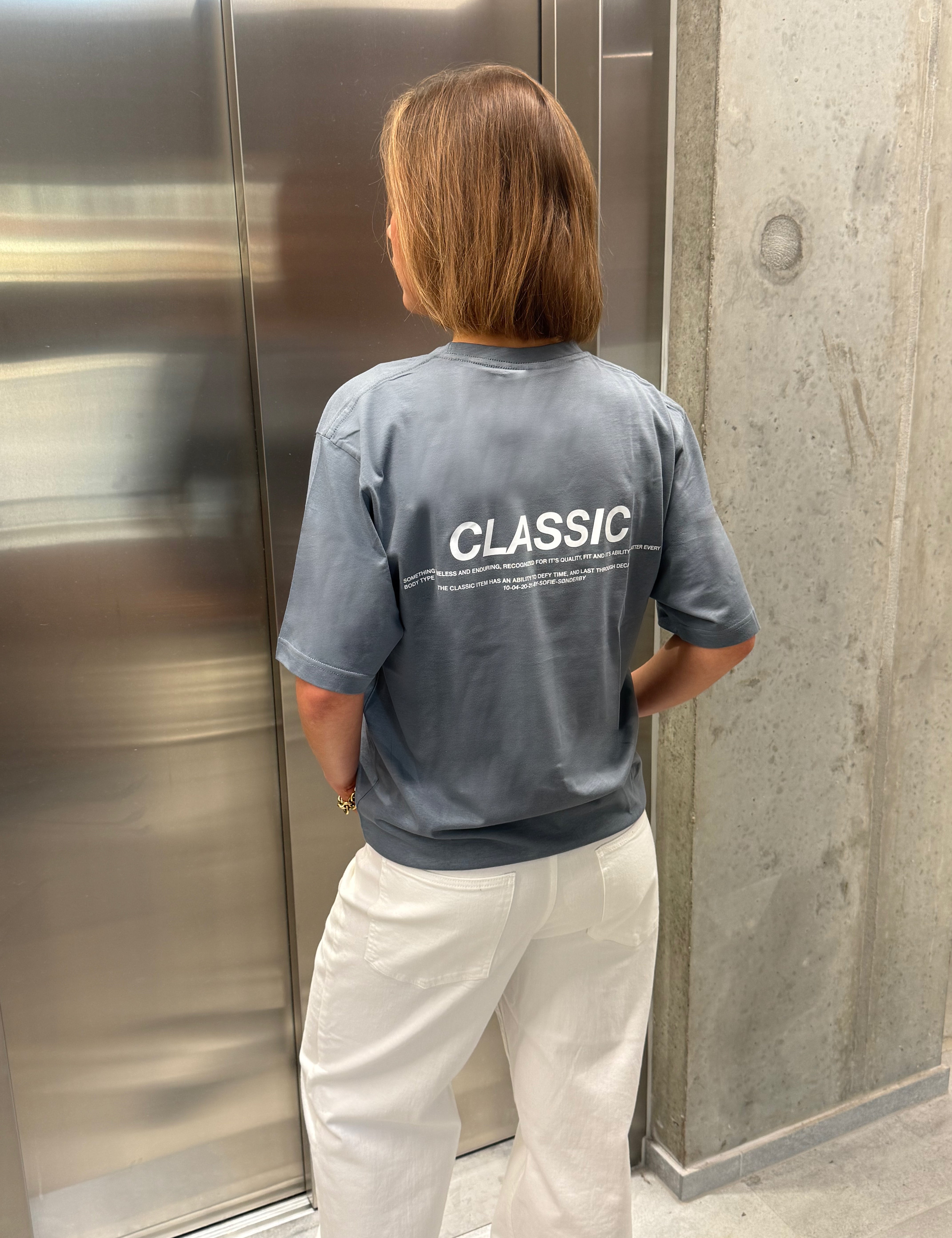 Stemningsbillede af pige der bærer en stone t-shirt med hvidt classic tryk og hvide NANNA jeans.  Fra BySofieSønderby