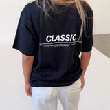 Modelfoto af pige i sort CLASSIC t-shirt med reflekstryk, samt hvide NANNA jeans. Alt er fra BySofieSønderby.