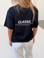 Modelfoto af pige i sort CLASSIC t-shirt med reflekstryk, samt hvide NANNA jeans. Alt er fra BySofieSønderby.