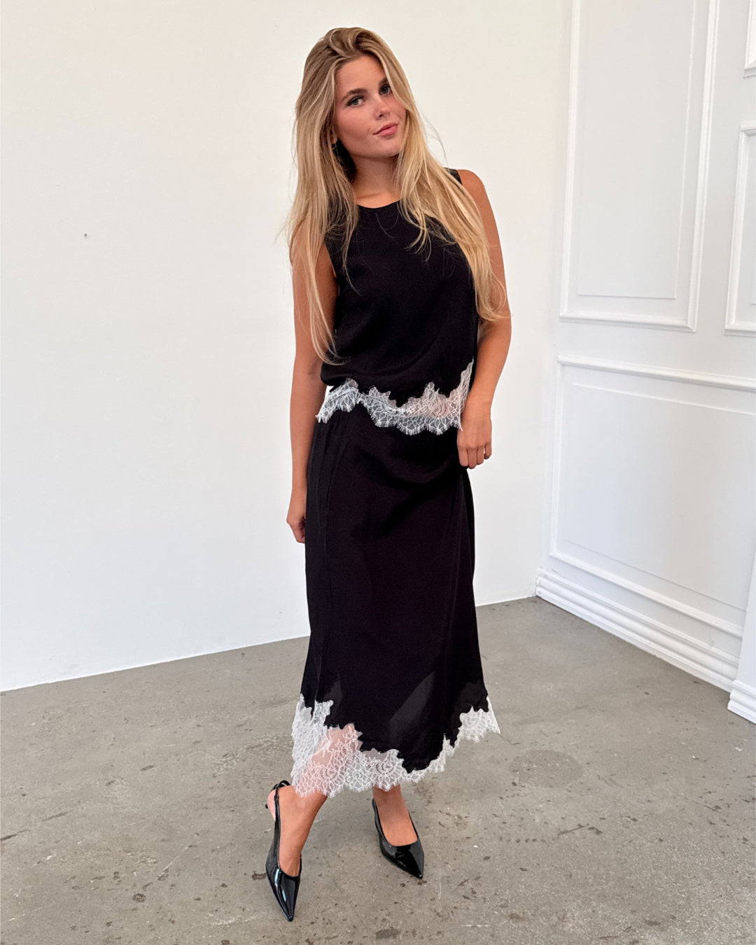 Modelfoto af pige i sort DALME nederdel med hvide blonder, samt matchende DALME top. Alt er fra BySofieSønderby.