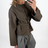 Modelfoto af pige i brun DARLA jakke med bindebånd, samt grå LISA bukser. Alt er fra BySofieSønderby.