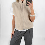 Modelfoto af pige i beige DAWN vest, hvid t-shirt og grå LISA bukser. Alt er fra BySofieSønderby.