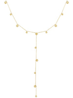 Kæde af guld med små kugler jævnt fordelt; en lang vedhængende sektion hænger centralt. Baggrunden er enkel og hvid, hvilket fremhæver smykkets elegante design.