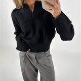 Person tager et billede med en mobiltelefon. De har en sort sweater og grå bukser på. Baggrunden er simpel og hvid.