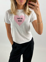 Kvinde tager selfie iført hvid t-shirt med lyserødt hjerte og teksten "DUMP HIM", mens hun står i et lyst rum.