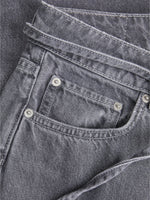 Grå jeans med synlige stikninger og metalnitter, der ligger fladt. Beliggende i en neutral baggrund uden tekst eller detaljer.