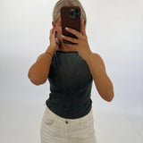 En person tager et spejlbillede med en smartphone. Personen bærer en sort top og hvide bukser. Baggrunden er hvid og minimalistisk.