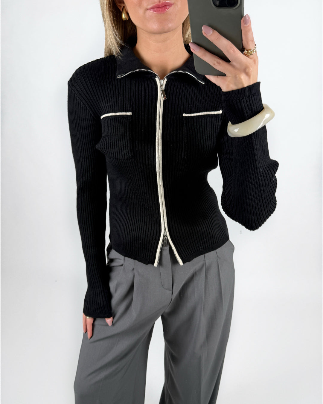 Modelfoto af pige i sort EMRYN zip-strik  og grå LISA bukser. Alt er fra BySofieSønderby.