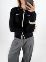 Modelfoto af pige i sort EMRYN zip-strik  og grå LISA bukser. Alt er fra BySofieSønderby.