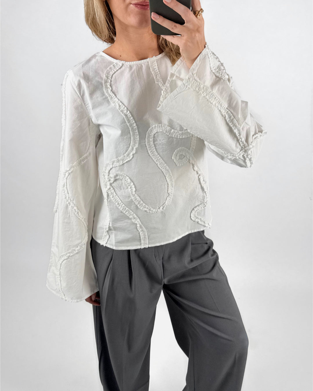 Modelfoto af pige med hvid ENESA skjorte, med detaljer, samt grå MILAN bukser. Set forfra. Alt er fra BySofieSønderby