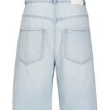 Lyseblå denimshorts vises fra bagsiden. De har to baglommer og et hvidt mærke på linningen. Korssting dekorerer lommerne. Baggrunden er ensfarvet hvid.