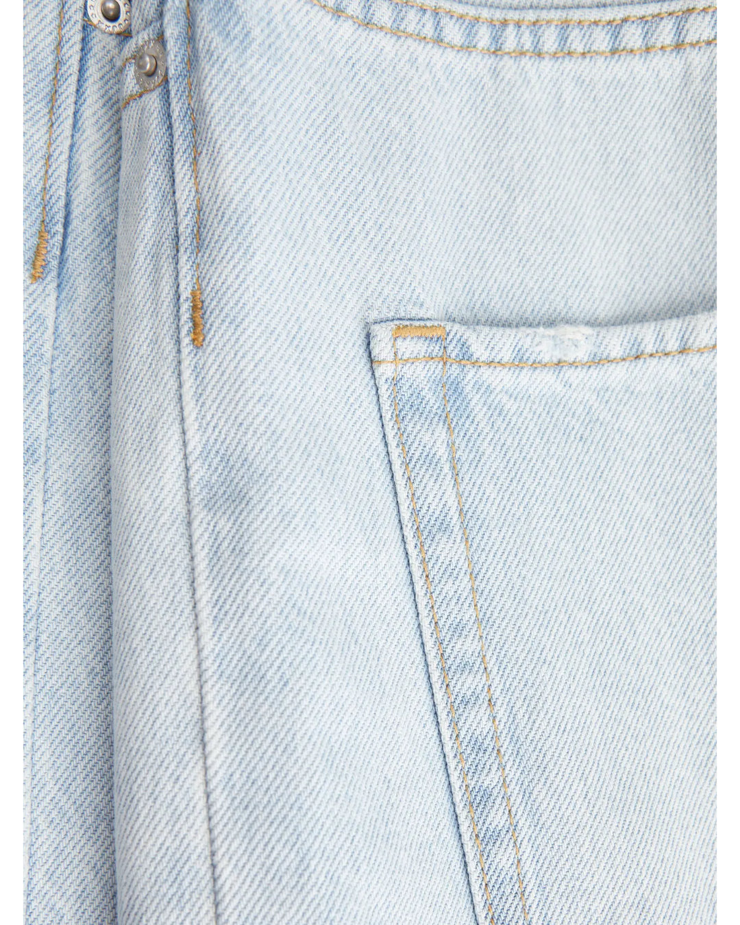 Stoffet er lys denim med gul syning, viser en synlig lomme og en metalknap i øverste venstre hjørne, i en tæt plan flade.