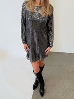 Modelfoto af pige i sølvfarvet FENJA kjole med pailetter, samt sorte støvler. Alt er fra BySofieSønderby.