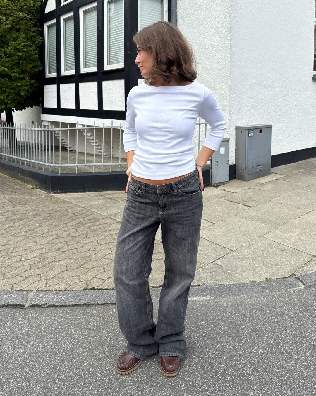 Modelfoto af pige i en hvid Fifi boatneck bluse og grå Nanna jeans. Alt er fra BySofieSønderby