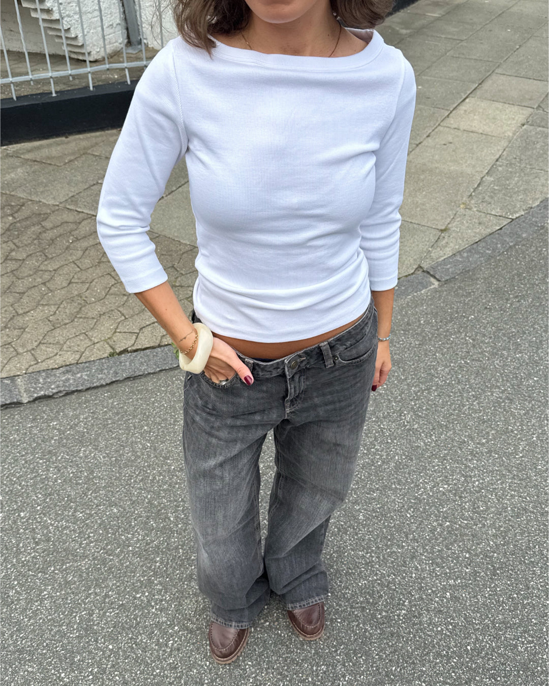 Modelfoto af pige i en hvid Fifi boatneck bluse og grå Nanna jeans. Alt er fra BySofieSønderby