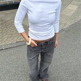 Modelfoto af pige i en hvid Fifi boatneck bluse og grå Nanna jeans. Alt er fra BySofieSønderby