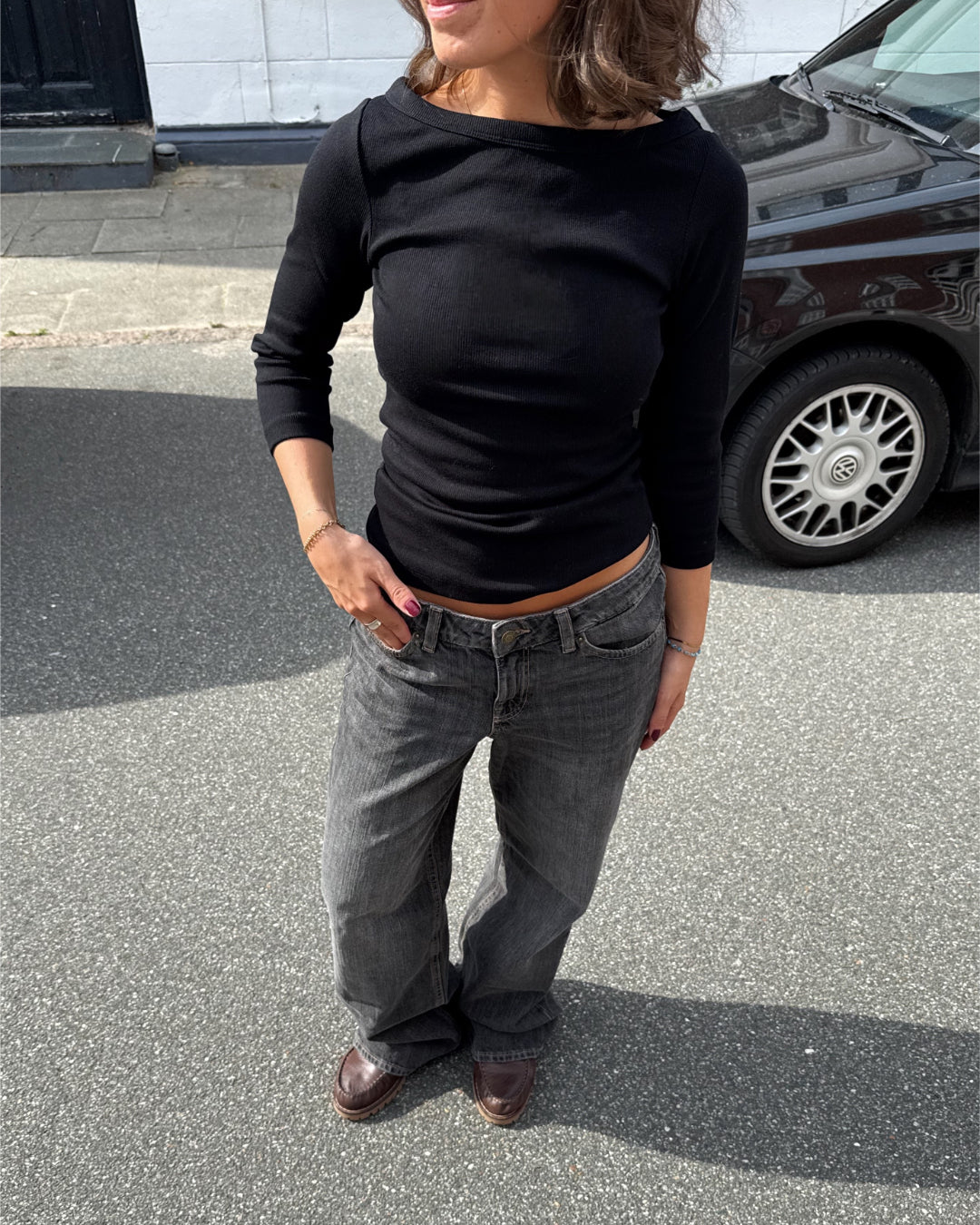 Modelfoto af pige i en sort Fifi boatneck bluse og grå Nanna jeans. Alt er fra BySofieSønderby