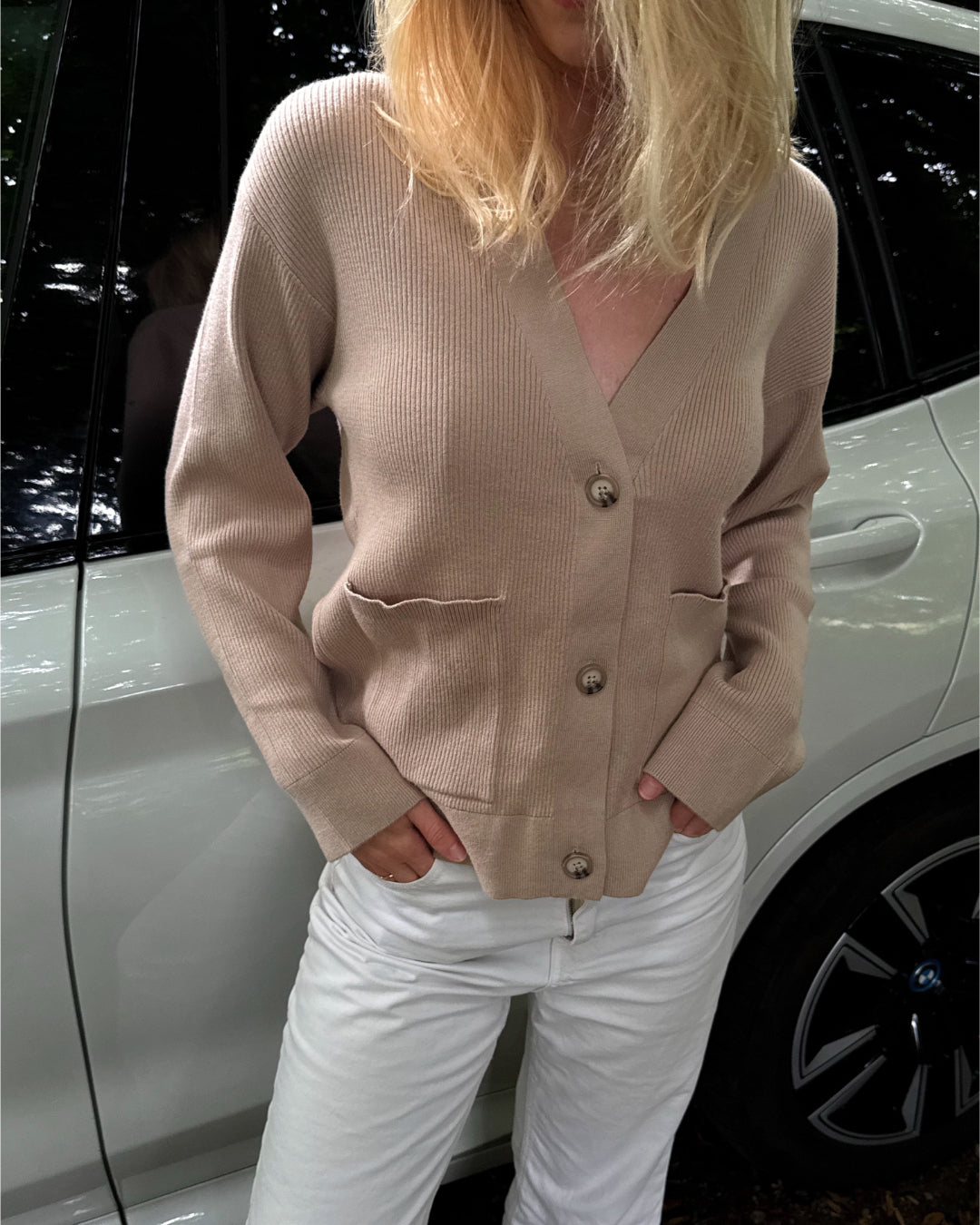 Modelfoto af pige i beige Franciska cardigan og hvide Nanna jeans. Alt er fra BySofieSønderby