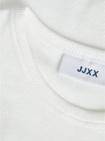 En hvid trøje med mærkatet "JJXX" syet ind i nakken, ligger fladt på en lys overflade.