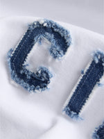 Detaljefoto af hvid Gigi t-shirt med denimblå Ciao bogstaver. På hvid baggrund. Fra BySofieSønderby