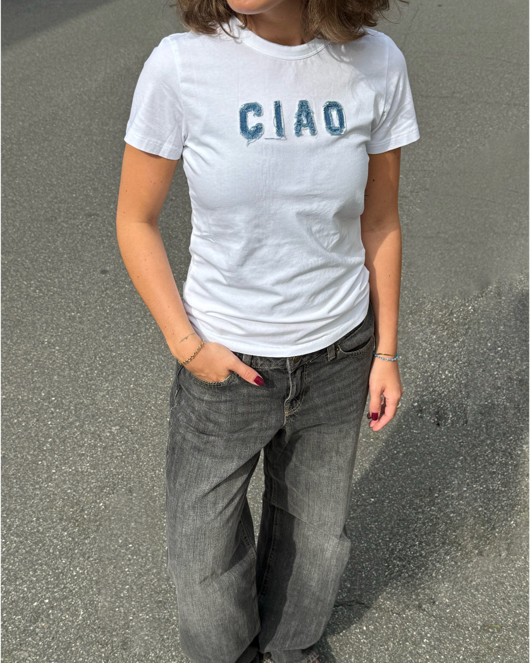 Modelfoto af pige i hvid t-shirt med Ciao syet på brystet, samt grå Palermo jeans. Alt er fra BySofieSønderby