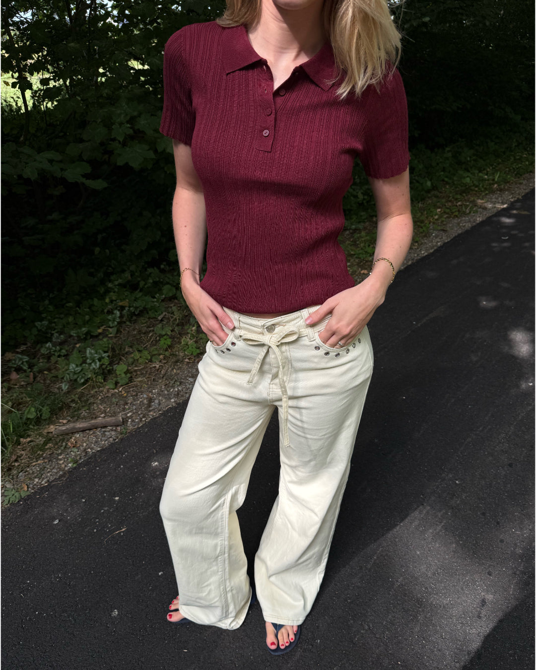 Modelfoto af pige i en bordeaux Hadley polo og cremefarvede Adrianna jeans. Alt er fra BySofieSønderby