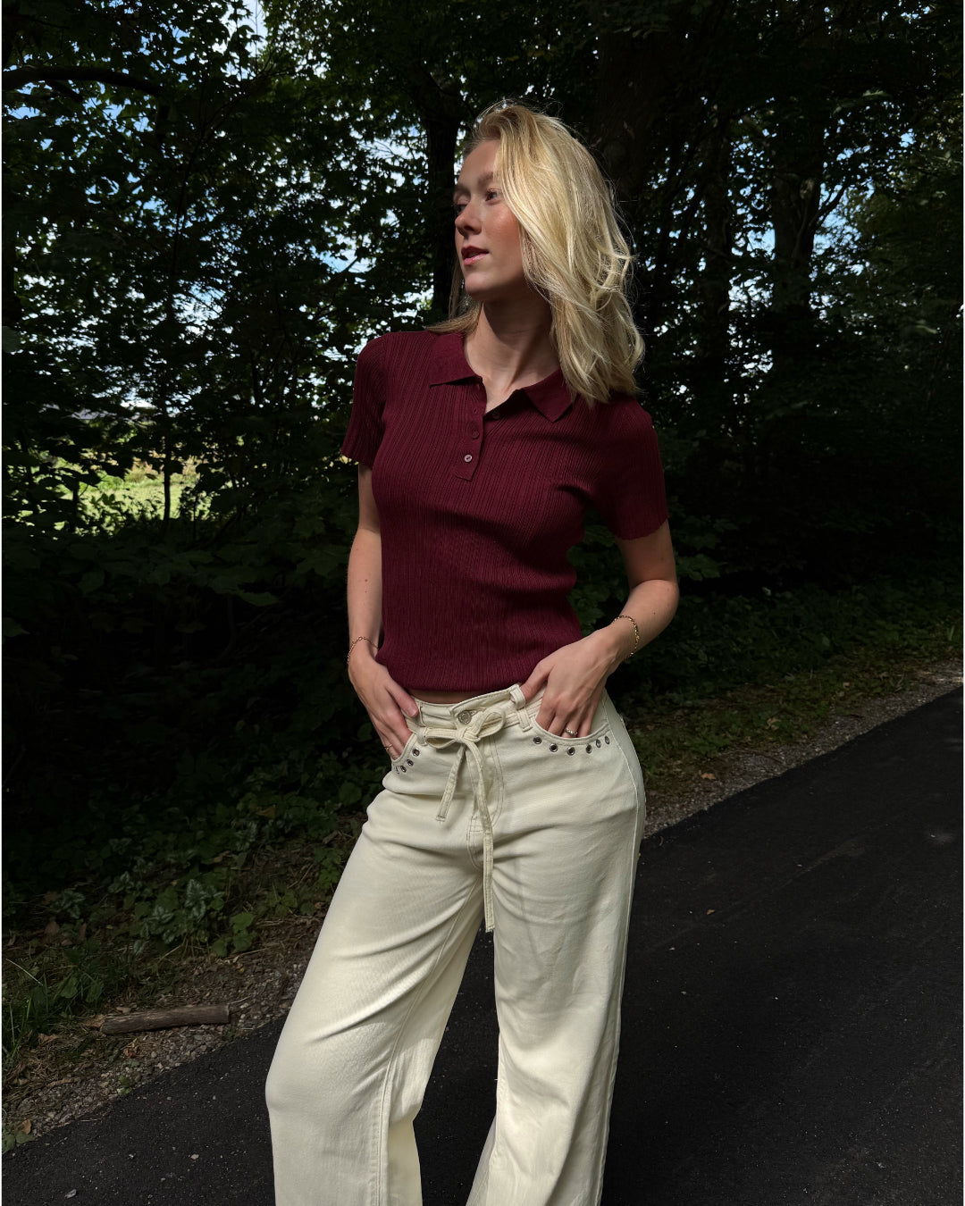 Modelfoto af pige i en bordeaux Hadley polo og cremefarvede Adrianna jeans. Alt er fra BySofieSønderby
