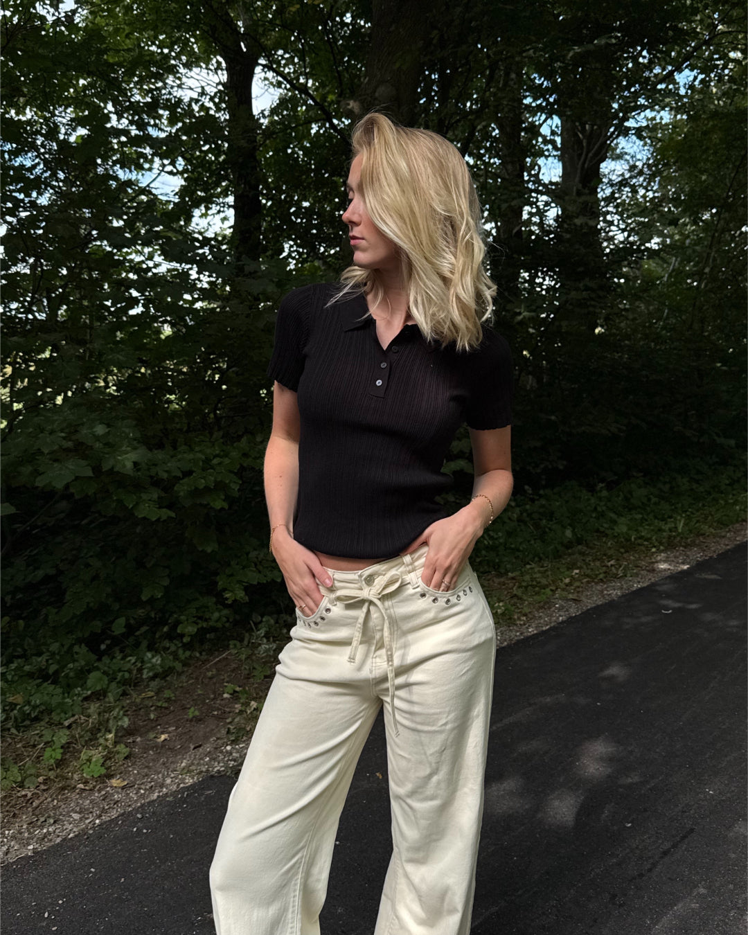 Modelfoto af pige i en sort Hadley polo og cremefarvede Adrianna jeans. Alt er fra BySofieSønderby