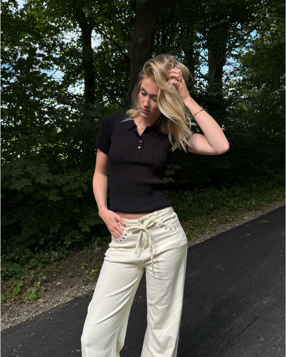 Modelfoto af pige i en sort Hadley polo og cremefarvede Adrianna jeans. Alt er fra BySofieSønderby