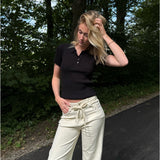 Modelfoto af pige i en sort Hadley polo og cremefarvede Adrianna jeans. Alt er fra BySofieSønderby