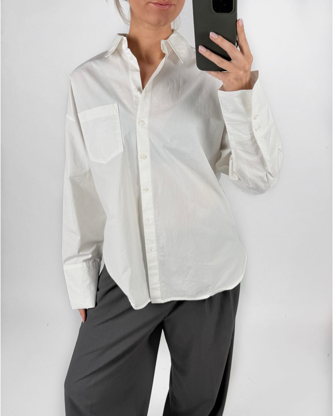 Modelfoto af pige i hvid HENNA skjorte med skrift-detaljer på ryggen, samt grå LISA bukser. Alt er fra BySofieSønderby.