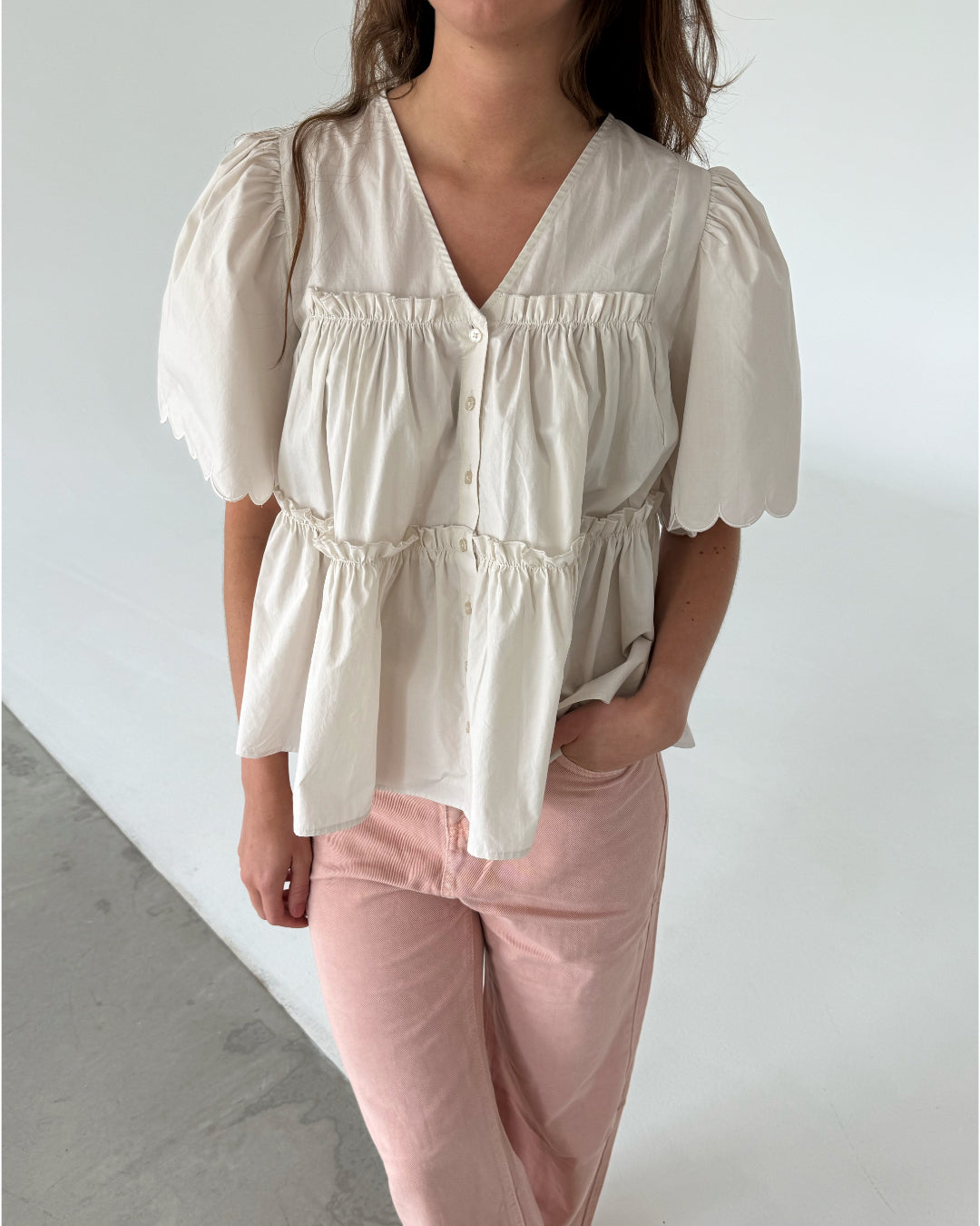 Modelfoto af pige som bærer creme-farvet HOPE top med v-hals og lyserøde jeans. Alt er fra BySofieSønderby