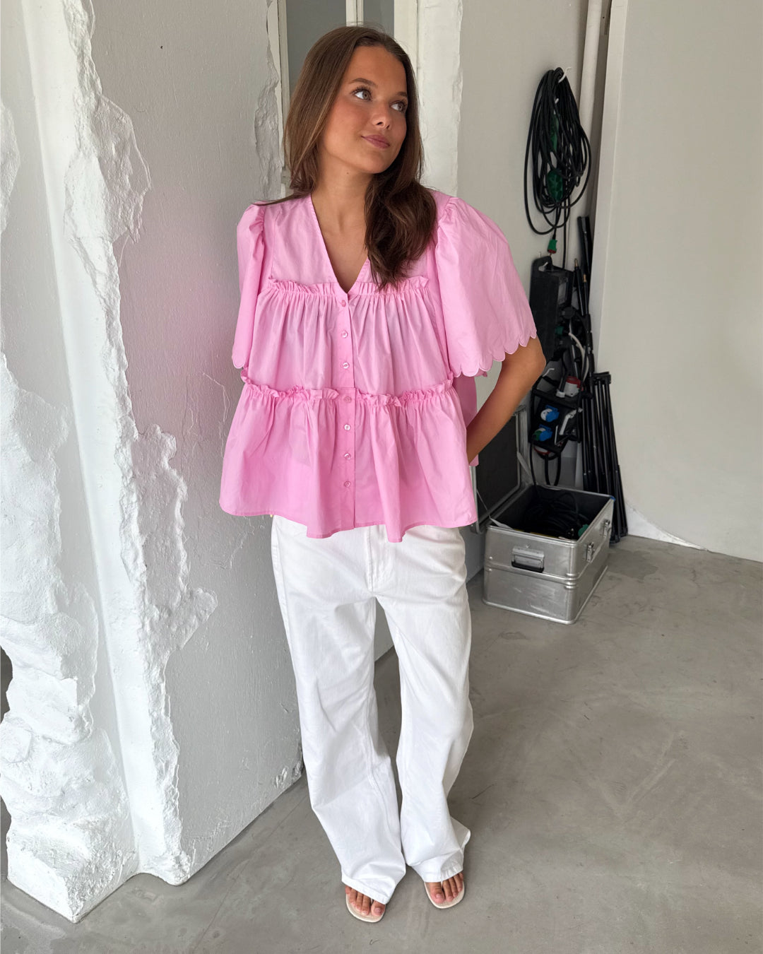 Modelfoto af pige som bærer lyserød HOPE top med v-hals og hvide jeans. Alt er fra BySofieSønderby