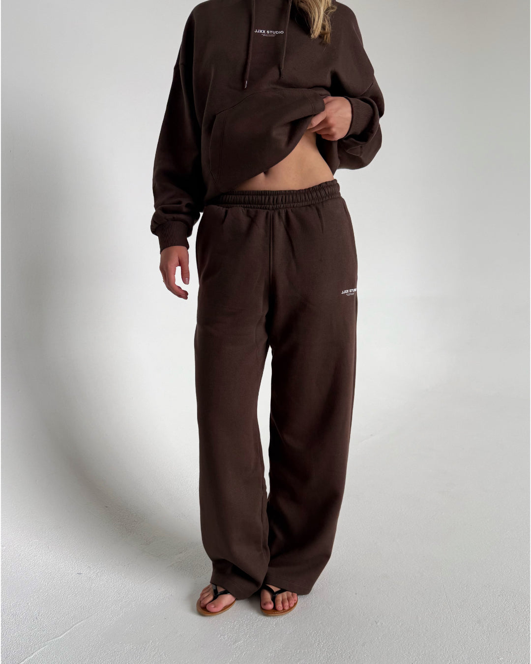 Modelfoto af pige som bærer en Studio Vesterbro bukser i brun, samt Studio Vesterbro hoodie i brun. Alt fra By Sofie Sønderby