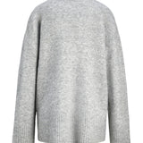 En grå sweater hænger frit, lavet af blødt, strikket materiale. Den har lange ærmer og en ribbet kant ved taljen og ærmeenderne, på en hvid baggrund.