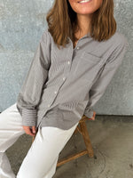 Modelfoto af pige der bærer en brun/hvid ternet Jamie Skjorte, samt hvide Nanna jeans. Alt fra BySofieSønderby