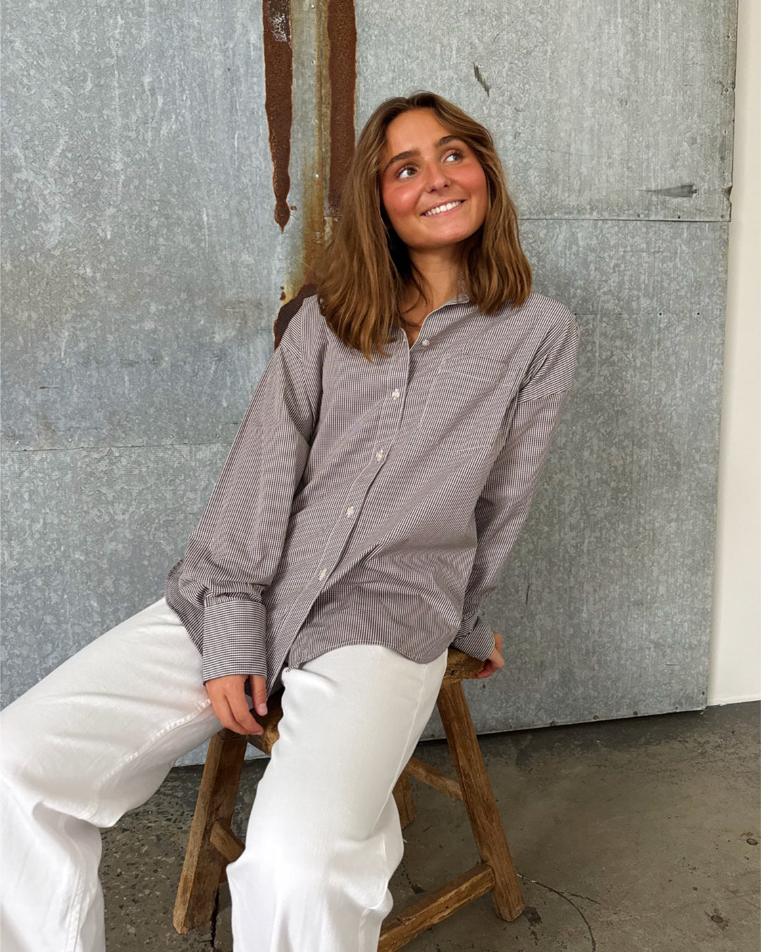 Modelfoto af pige der bærer en brun/hvid ternet Jamie Skjorte, samt hvide Nanna jeans. Alt fra BySofieSønderby