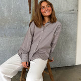Modelfoto af pige der bærer en brun/hvid ternet Jamie Skjorte, samt hvide Nanna jeans. Alt fra BySofieSønderby
