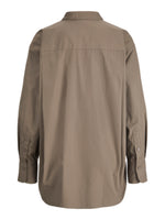Skjorte med lange ærmer og knapper ved manchetterne, i en neutral beige farve. Set bagfra, uden synlige dekorationer, hænger løst i en hvid baggrundskontekst.