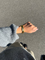 Modelfoto af en Jazlyn guld armbånd. Baggrund er grå. Fra BySofieSønderby