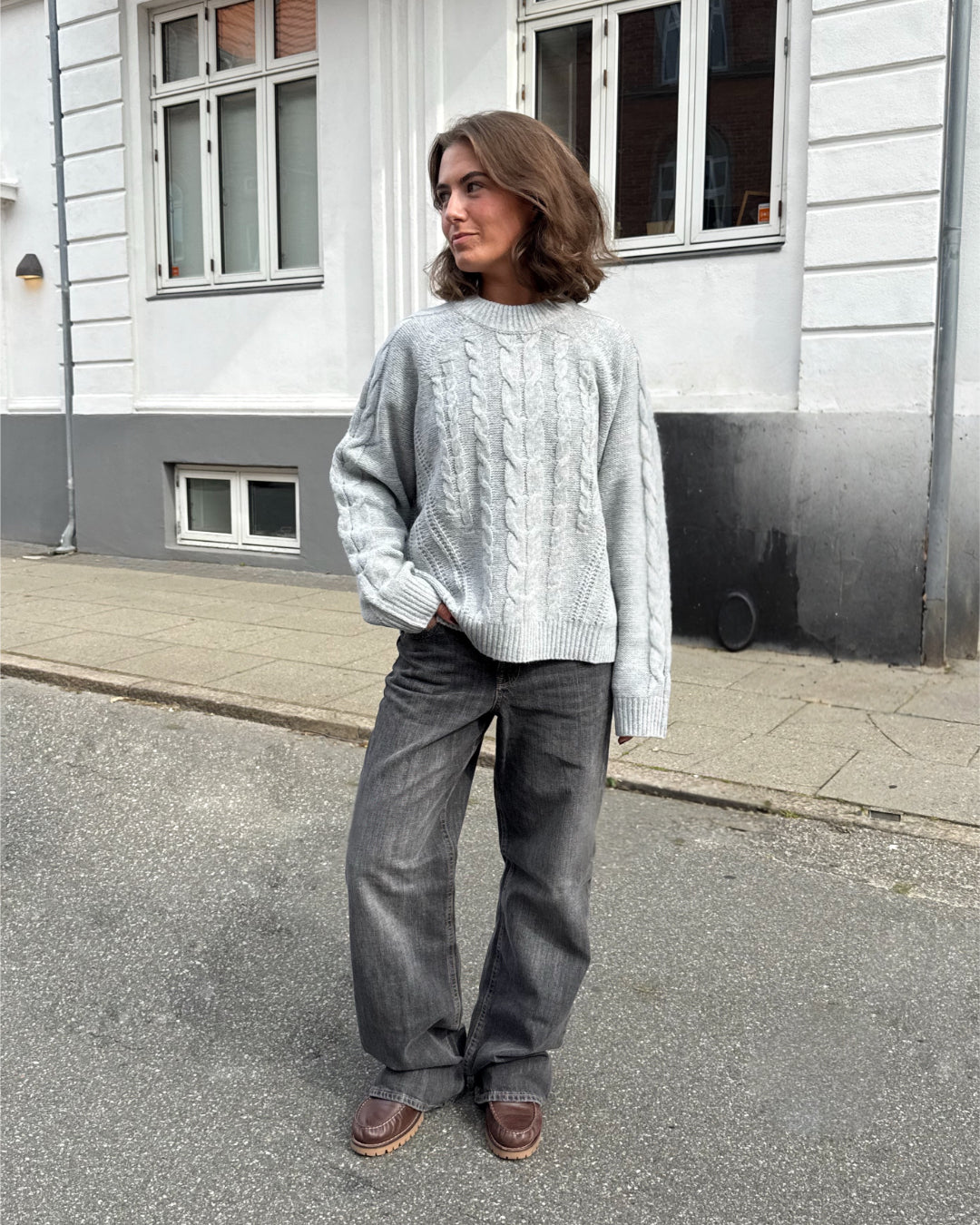 Modelfoto af pige i grå Josie striktrøje, samt grå Palermo jeans. Alt er fra BySofieSønderby