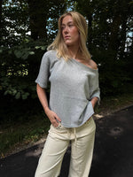 Modelfoto af pige i grå Karsyn wideneck  t-shirt og cremefarvede Adrianna jeans. Alt er fra BySofieSønderby